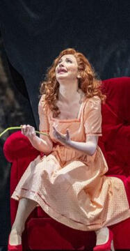Marie Hänsel in einem rosa Kostüm mit einer Rose in der Hand